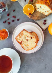 Slices of cake with candied fruit and dried cranberries, served on a round white plate, for tea. Cupcake on a gray background top view.