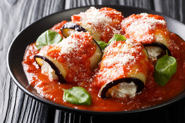 Baked eggplant rolls with ricotta in tomato sauce and served with parmesan and basil close-up in a plate. horizontal