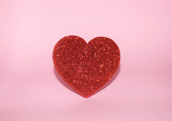 Valentine's Day love concept, single red glitter heart on pink background. St. Valentine's Day concept background with copy space. Valentine's Day background