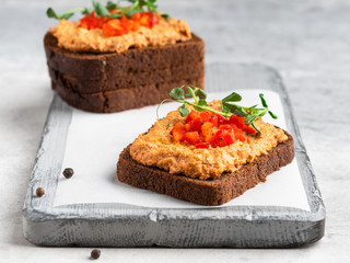 Healthy vegetarian rye bread open sandwich with vegetable pate (paste) decorated with chopped red pepper and micro greens. 