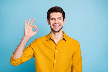 Photo of cool guy showing you ok sign to recommed good to purchase smiling toothily isolated over pastel blue color background