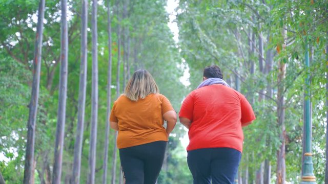 Back view of overweight couple doing workout by running together at the park. Shot in 4k resolution