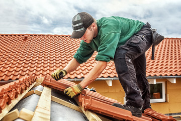 Roofer at work, installing clay roof tiles, Germany - 315602970