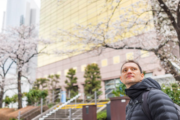 Fototapeta na wymiar Tokyo, Japan - March 30, 2019: Sumida park Asakusa district area with man looking up by cherry blossom trees in spring and building