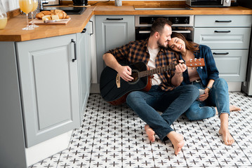 Young couple in love in the kitchen with a guitar