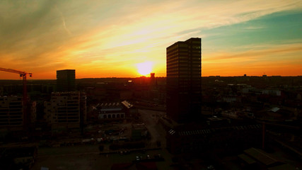 City with tall houses shrouded in darkness against the backdrop of a bright sunset