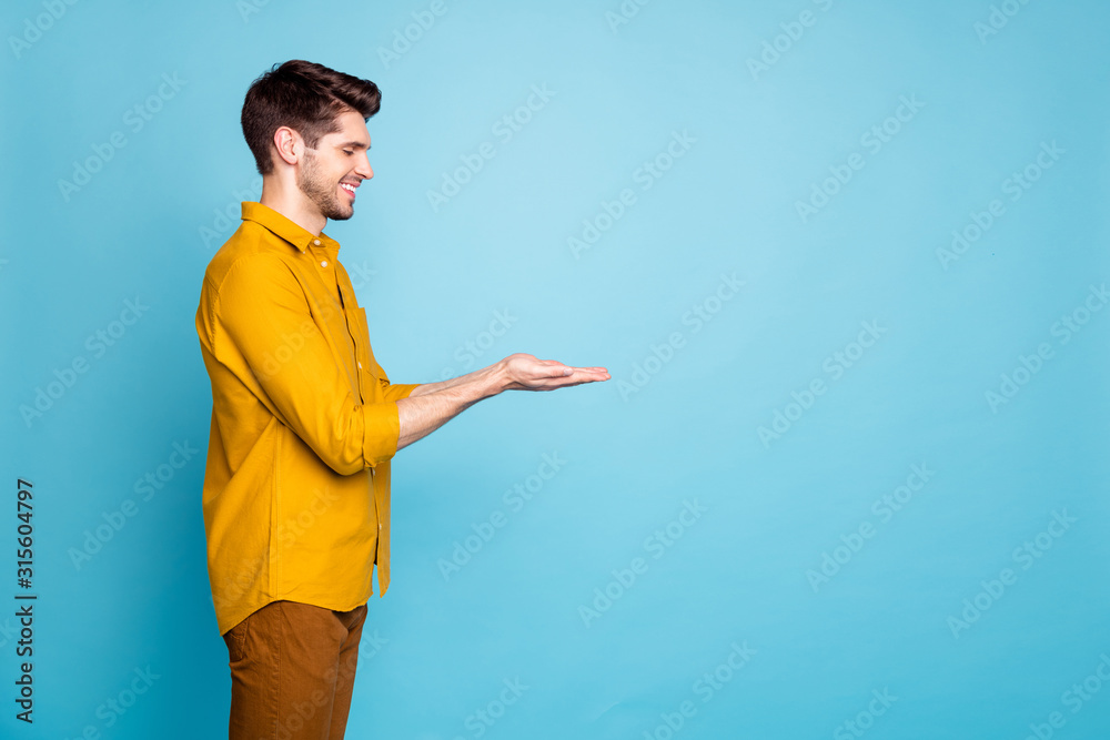 Poster photo of adoring man holding object with hands wearing yellow shirt trousers pants smiling toothily 