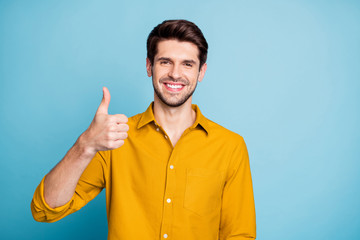 Photo of cheerful handsome funny funky guy smiling toothily showing you thumb up demonstrating quality of product isolated over pastel color background