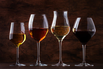Wine tasting concept, still and sparkling wines. Red, white wine, rose and champagne in wine glasses on vintage wooden table background