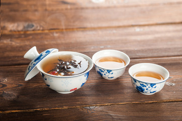 Knitted blooming tea in a porcelain teapot close-up. Tea ceremony on a dark wooden background and copy space.