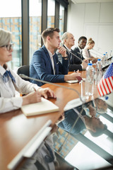 Multiethnic group of business people sitting at the table and discussing during press conference