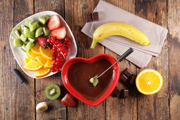 delicious chocolate fondue with fresh fruit in red heart bowl