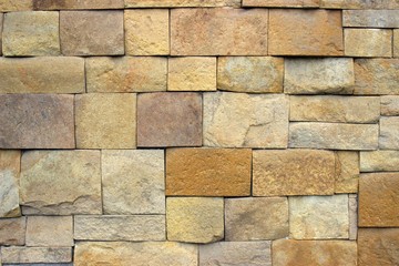  Wall of tan, densely laid stone of square and rectangular shape