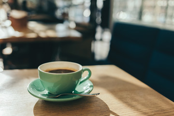 Cup of morning coffee on a wooden table in a cafe.