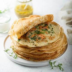 Traditional Russian pancakes with salmon and herbs