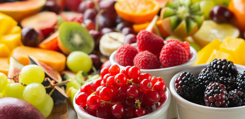 Long photo, banner, healthy cut fruits background, strawberries raspberries oranges plums apples kiwis grapes red currants blueberries mango persimmon, selective focus