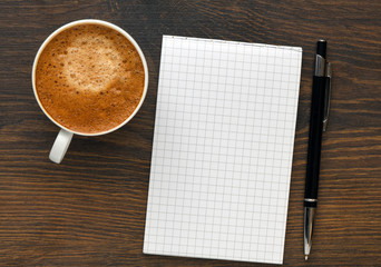 Top view of empty notebook, pen and coffee on the wooden table. Blank notepad for drawing with copy space. Creative space and artwork.