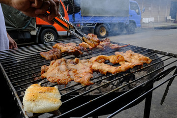 Grilled pork and Chicken wings on the roaster in street food stall, local Thai street food style. with selective focus
