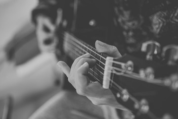 Close up view of hands playing guitar in black and white. 