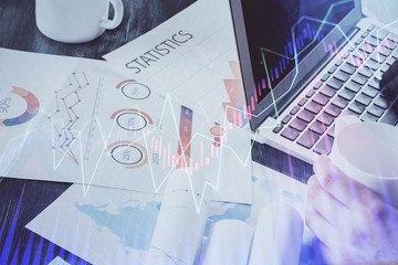 Double exposure of stock graph with businessman typing on computer in office on background. Concept...