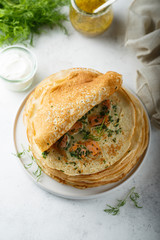 Traditional Russian pancakes with salmon and herbs
