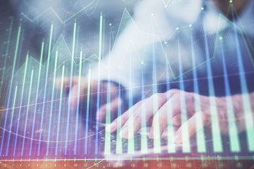 Forex graph with businessman typing on computer in office on background. Concept of analysis. Double exposure.