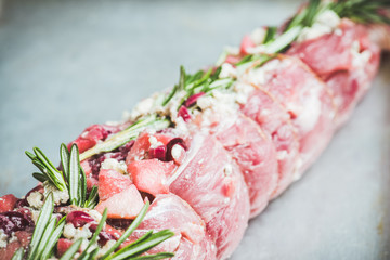 Raw pork loin with fruits, blue cheese and rosemary ready for baking. Selective focus. Shallow depth of field.