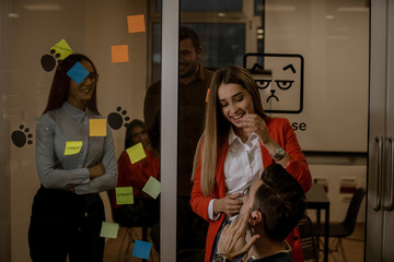 Startup business people group working everyday job at modern coworking office space. business, startup, planning and people concept - happy creative team writing on stickers at office glass board