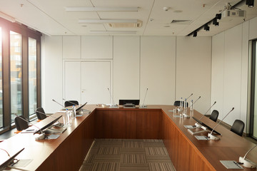 Image of big table with monitors and microphones for speakers in conference hall at office building