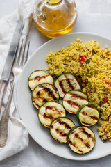 tabbouleh and grilled courgette on white plate on ceramic background