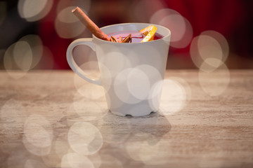 Mug with mulled wine stands on an old wooden table. Selective focus, blur. Festive mood with beautiful bokeh
