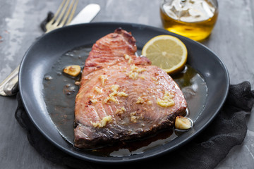 fried tuna with salt and lemon on dark plate