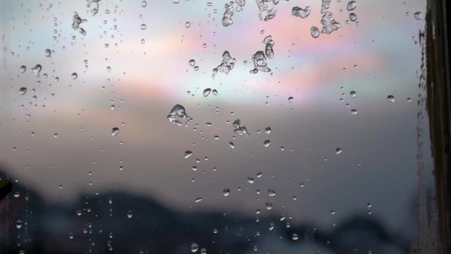 Beautiful raindrop on a window with colorful clouds in the background