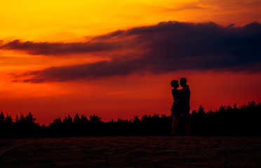 Girl and guy holding hands and sit on the shore of a forest lake. beautiful view of the lake . back view.