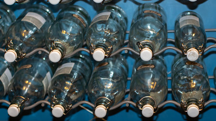 A metal holder for glass bottles, a shelf. Many empty transparent glass bottles with a sealed lid for preservation, closeup.