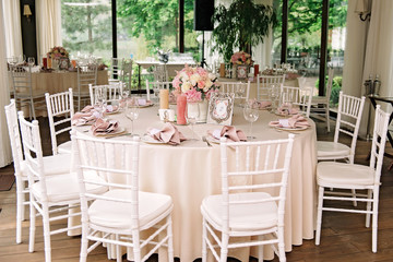 Wedding. Banquet. The chairs and round table for guests, served with cutlery, flowers and crockery and covered with a tablecloth
