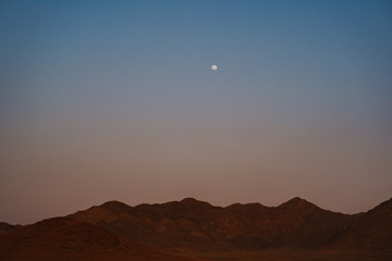 moon over NamibRand mountains in Namibia, Africa