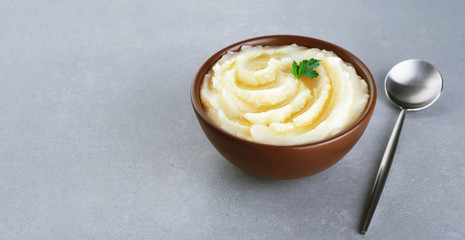 Mashed potatoes with butter and parsley on gray texture.