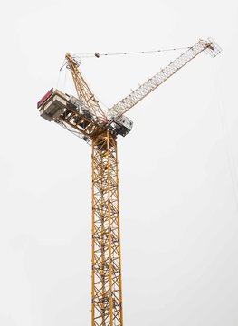 Leeds, England, 03/05/2019 Isolated image of the top of a yellow industrial construction crane with cement counter weight used for lifting heavy objects and parts of buildings that are very tall
