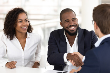 Happy black couple handshake banker getting acquainted at meeting