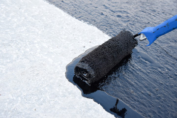 Worker applies bitumen mastic on the foundation