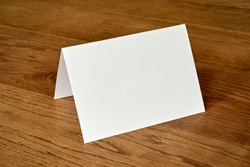 Standing blank empty greeting card mock up on dark wooden background. For use as a Christmas,...