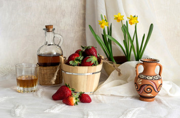 Still life with strawberries, brandy and daffodils on a table close-up