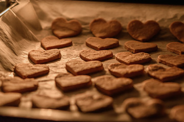 baking homemade cookies hearts on white parchment paper in the oven