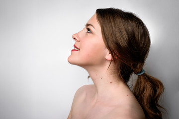 Beauty portrait of female face with natural skin on gray background.