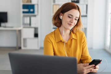 Young businesswoman listening to music on a mobile