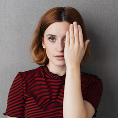 Serious young woman looking with one eye