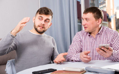 Obraz premium Happy male friends using phone at home table