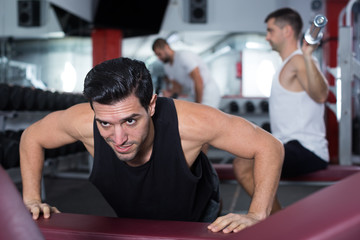 Man doing incline push-ups in gym