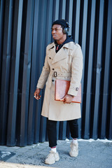 African american man with headphones, wear on hat and coat listening music on steel background.